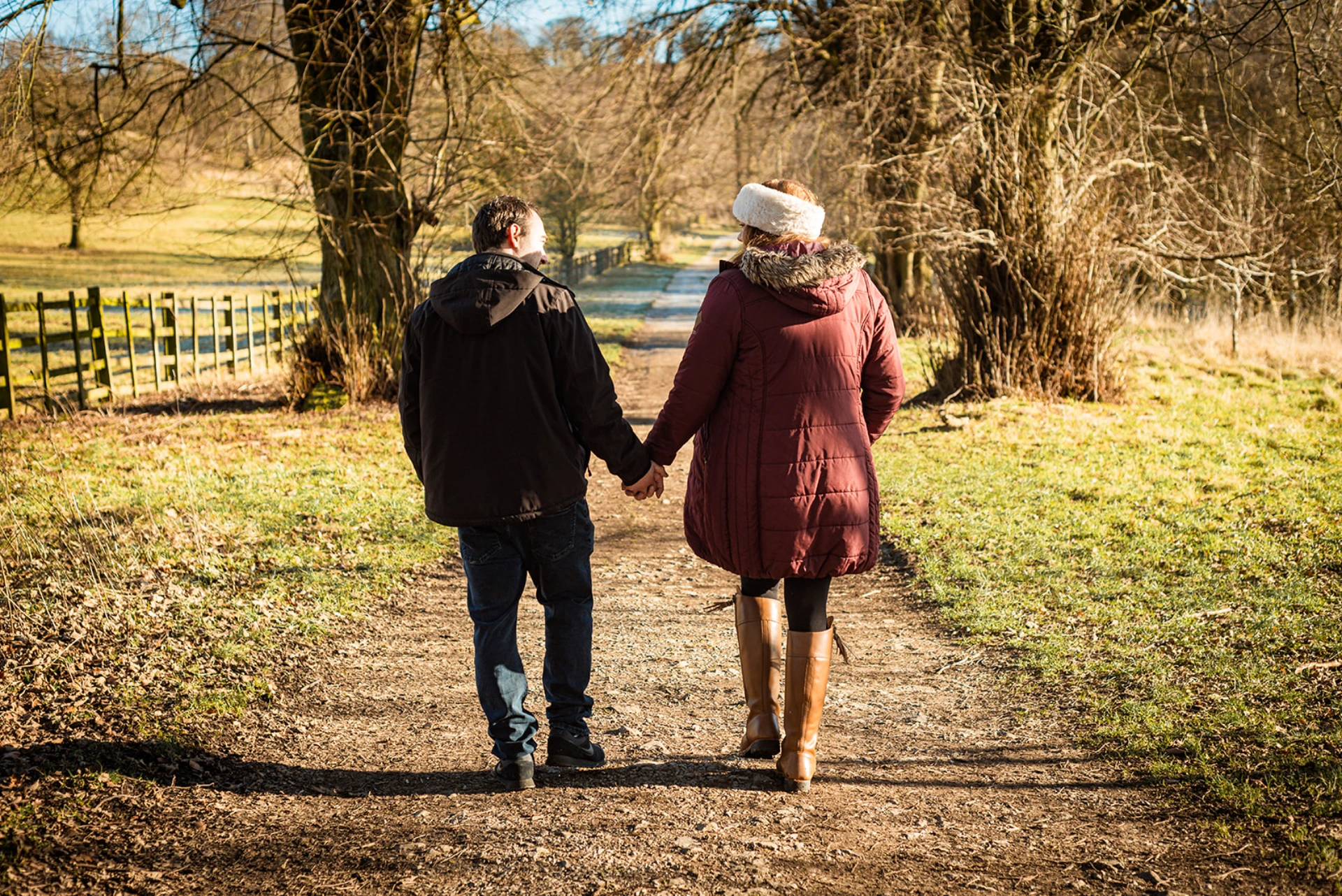 A couple walking hand in hand along a countryside path